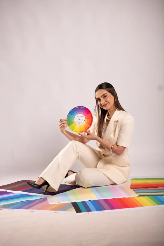 Shauana sentada sobre o painel de cartelas de cor, com o círculo cromático nas mãos